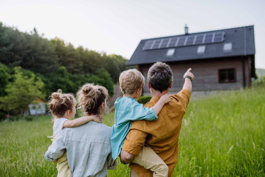 Familie neben ihrem mit ReGeTECH Photovoltaik-System ausgestatteten Zuhause, zeigt Nachhaltigkeit.